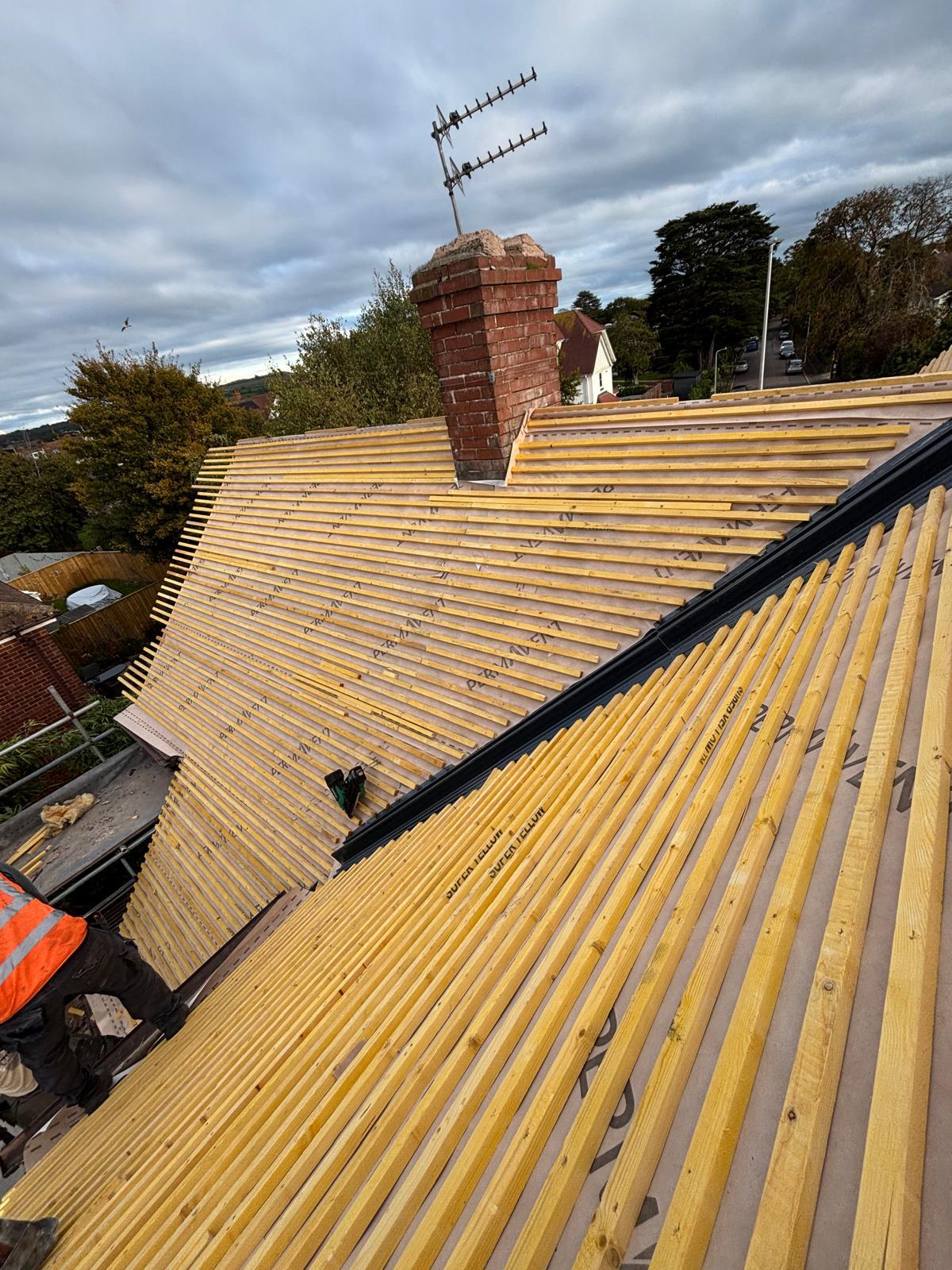 Full roof strip in progress — new battens ready for tiles across a hip end