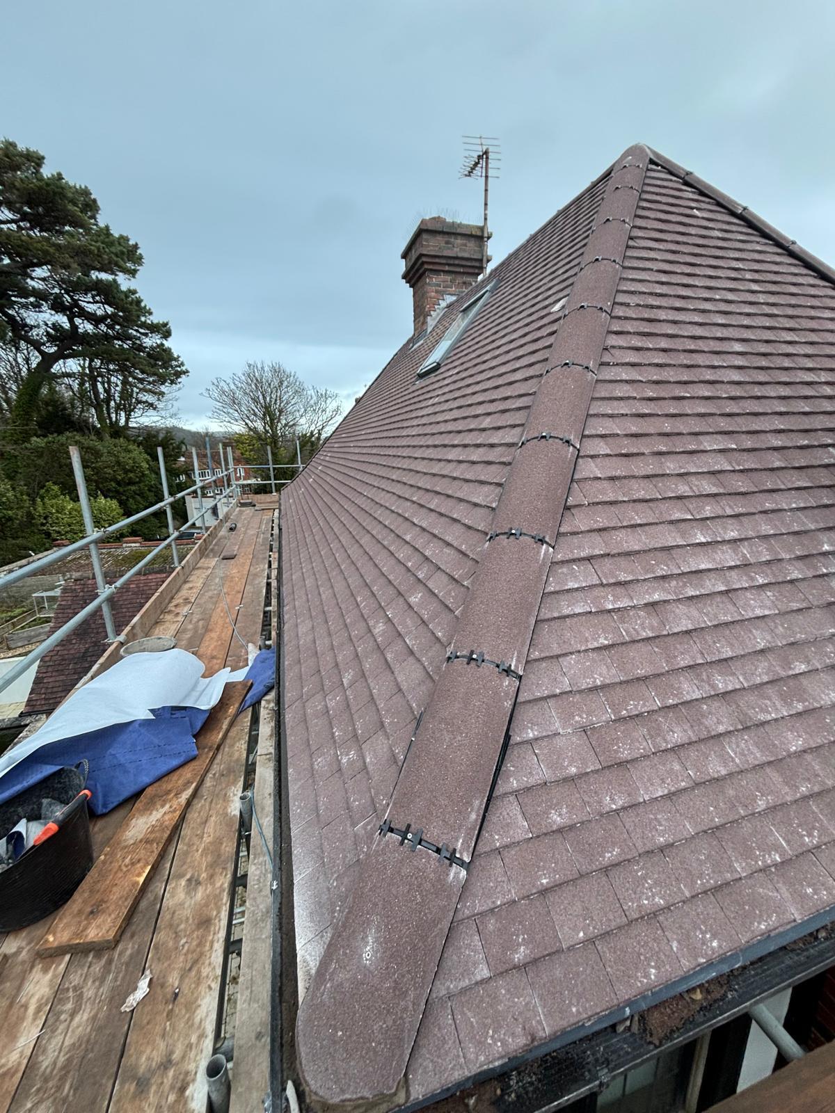 Newly completed brown plain-tile roof with chimney detail