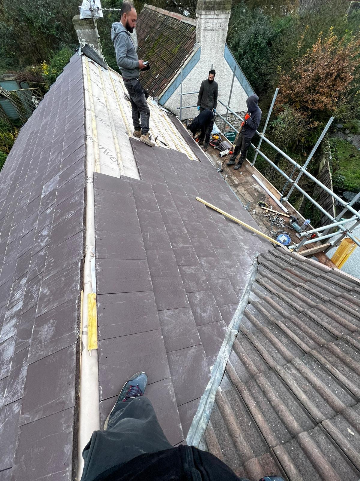 Slate re-roof in progress — team laying new slates over breathable membrane