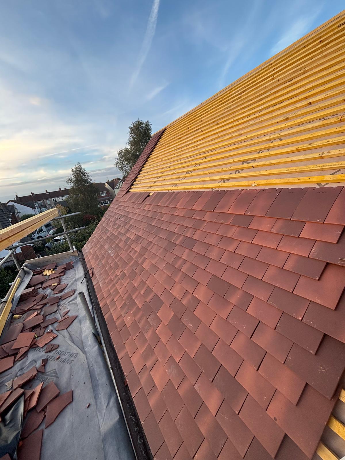 New clay plain tiles being laid over freshly counter-battened roof